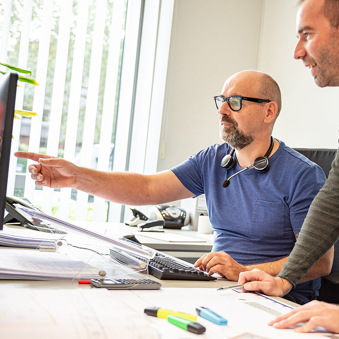 Zwei Mitarbeitende schauen auf einen Bildschirm