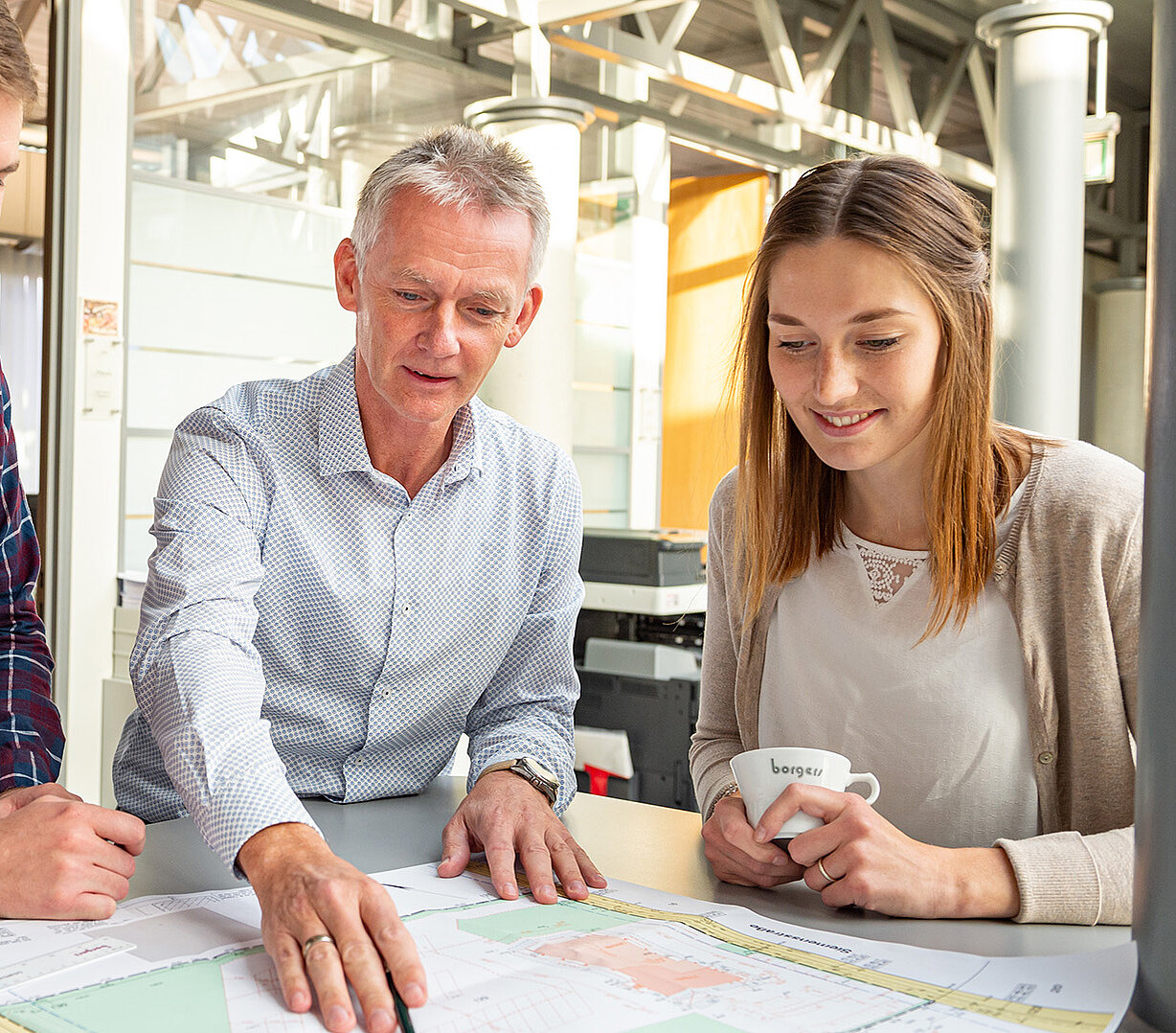 4 Mitarbeitende blicken auf einen Bauplan