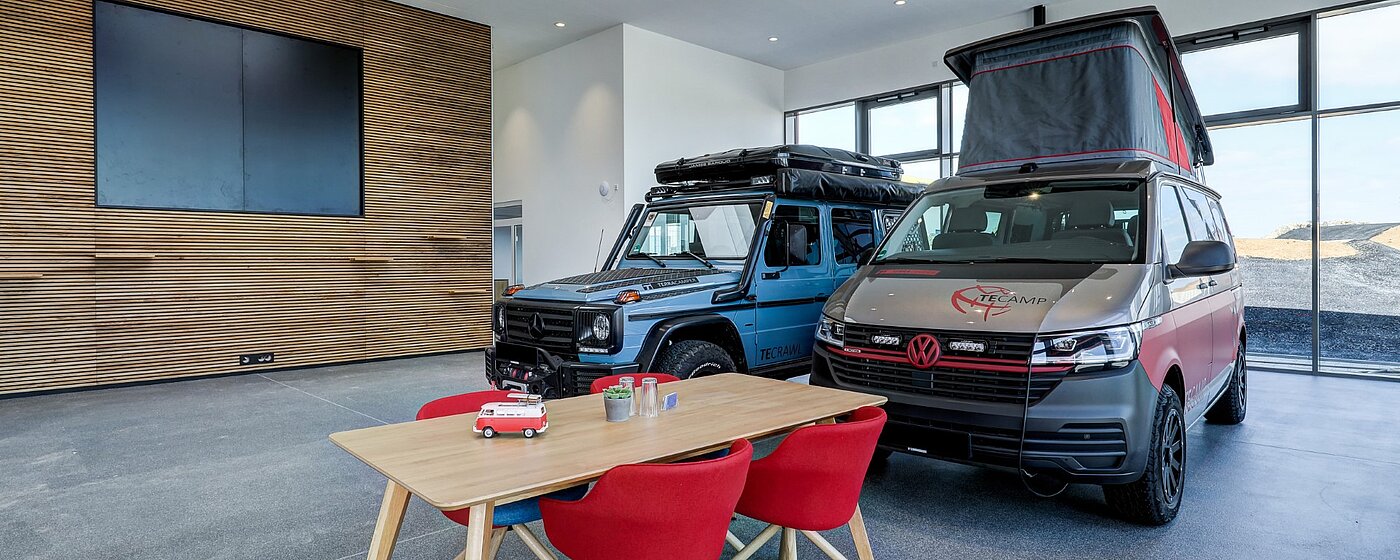 Moderner Showroom mit Camper-Van und Jeep und Tisch für Kundengespräche
