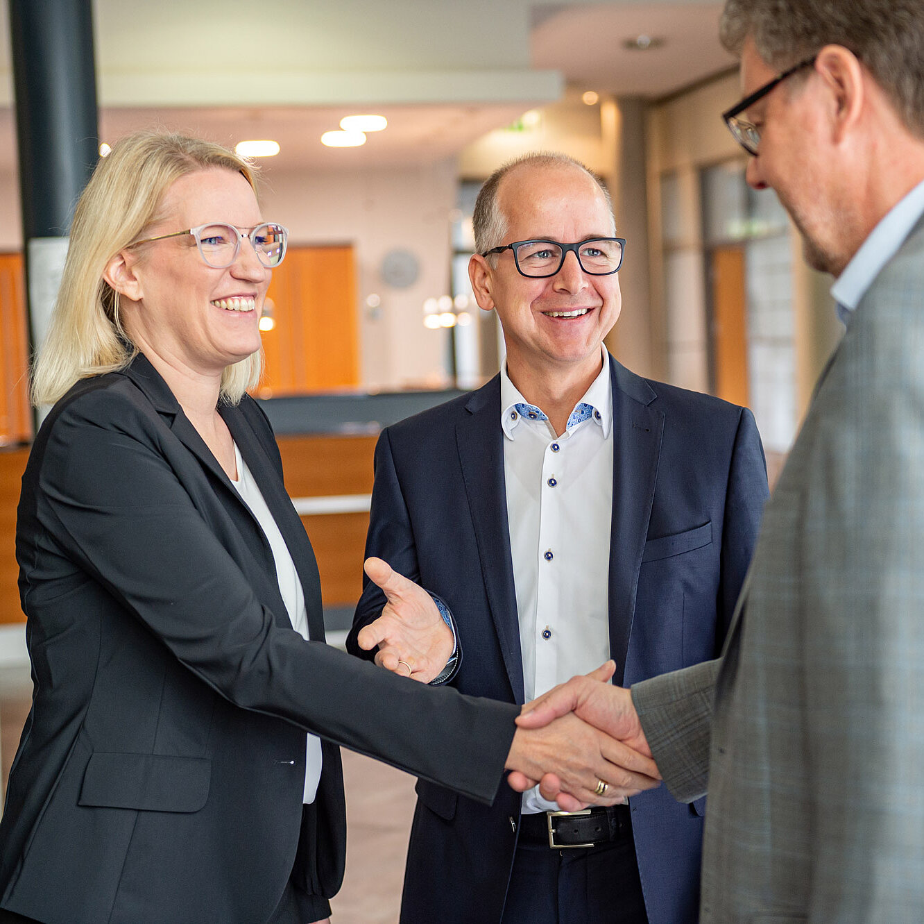 Die Geschäftsleitung reicht einem Herrn partnerschaftlich die Hand